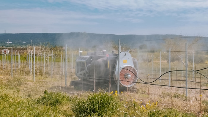 An autonomous vehicle kicking up dust in an orchard