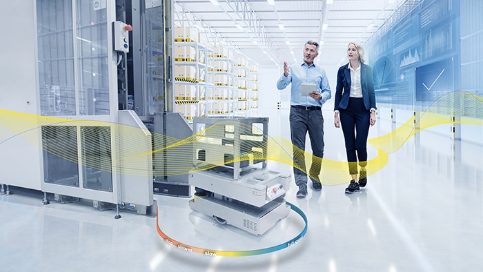 A man crosses the path of an automated guided vehicle in a production facility and is reliably detected.