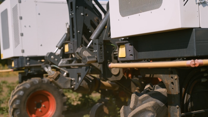 Agricultural machine operating on a field with sensors installed at the front.